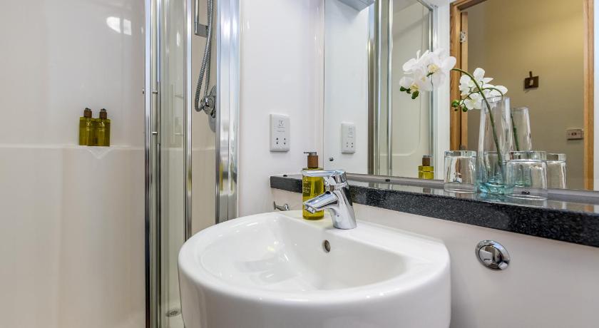 a white sink sitting under a mirror in a bathroom, Richmond Place Apartments in Edinburgh