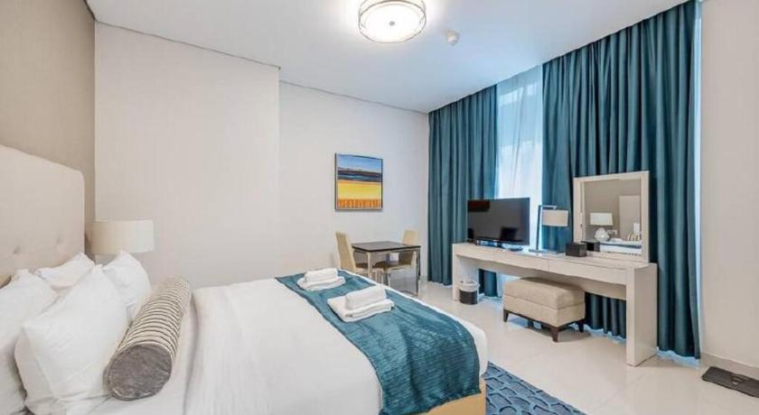 a hotel room with a bed, desk and television, DAMAC Maison Cour Jardin in Dubai