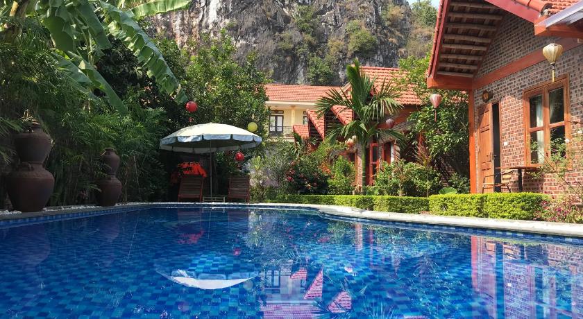 a pool with a blue umbrella in the middle of it, Tam Coc Friendly Homestay in Ninh Bình