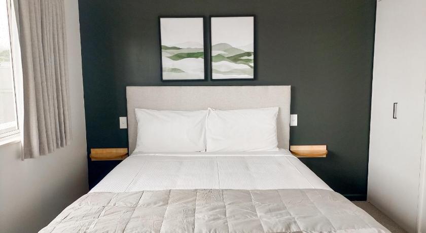 a bed with white sheets and a white comforter, Boutique Motel in Nelson