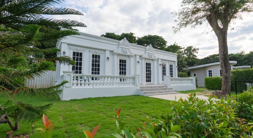 a large white house sitting in the middle of a grassy area, Je t'aime cafe & villa in Sing Buri