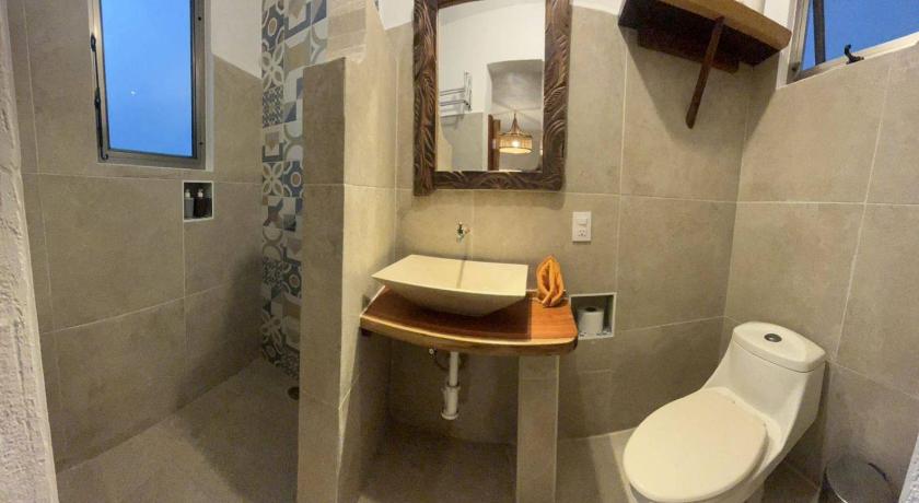 a bathroom with a toilet a sink and a mirror, Casa Lamat in Bacalar
