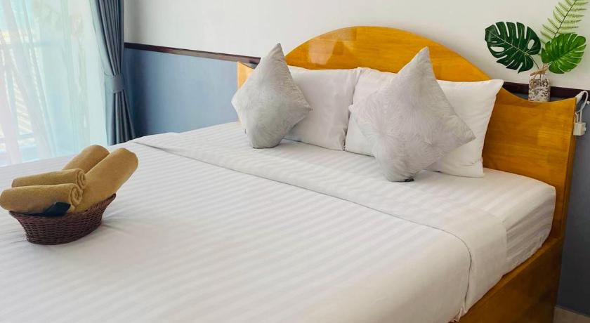 a bed with a white comforter and pillows, Baan Tip Su Kon in Pattaya