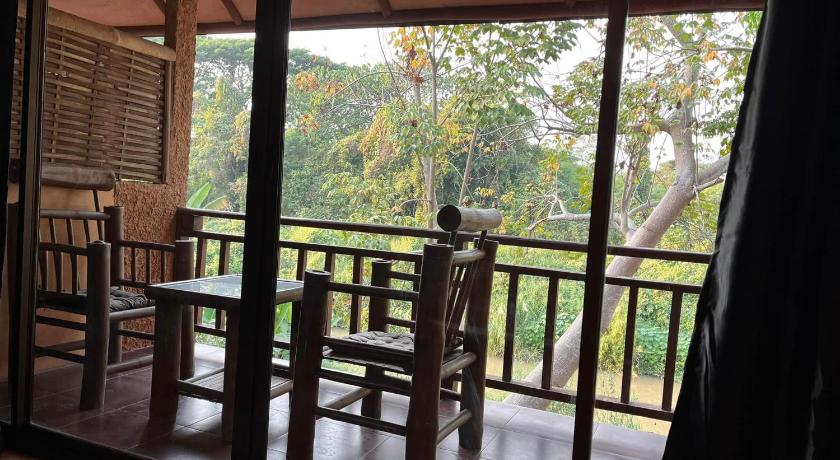 a person sitting on a bench in front of a window, Akha River House in Chiang Rai