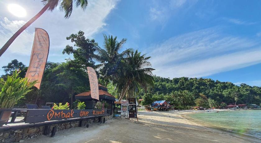a beach scene with a surfboard and palm trees, Ombak Dive Resort in Perhentian Islands
