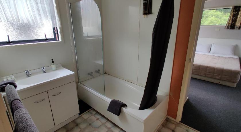 a bathroom with a tub, toilet and sink, Motel Villa del Rio in Whangarei