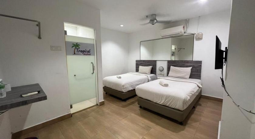 a hotel room with a bed and a dresser, Tropical Hotel Kota Damansara in Kuala Lumpur