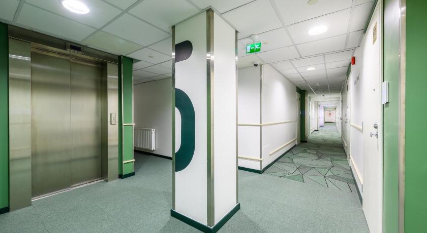 a man standing in a hallway next to a door, Forenom Aparthotel Oulu in Oulu
