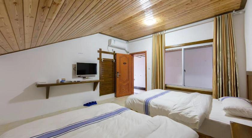 a hotel room with two beds and a television, A'lin Country Guest House in Zhangjiajie