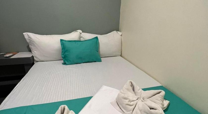 a bed with white sheets and pillows on top of it, Laule'a Hostel in Palawan