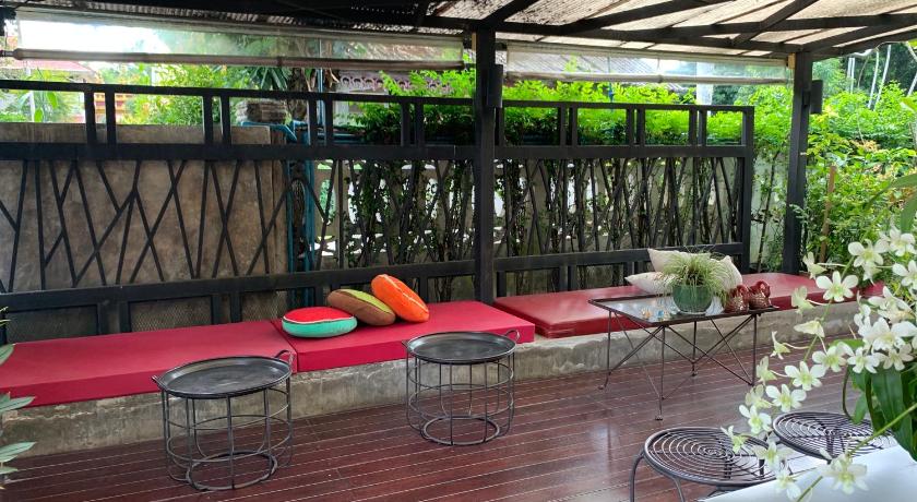 a patio area with tables, chairs, and umbrellas, Homey Dormy Chiangrai in Chiang Rai
