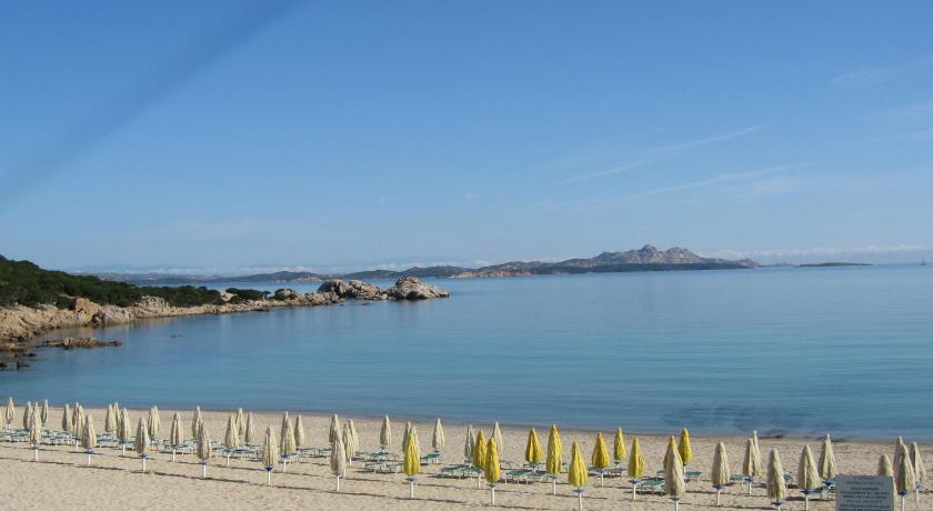 a beach with a fence and a lighthouse, Hotel 3 Botti in Baja Sardinia