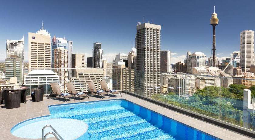 a blue and white swimming pool with blue umbrellas, Pullman Sydney Hyde Park in Sydney