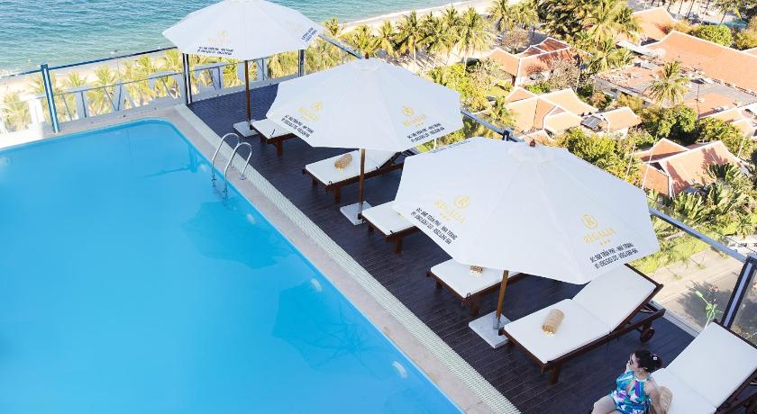 a beach area with chairs, tables and umbrellas, Regalia Nha Trang Hotel in Nha Trang