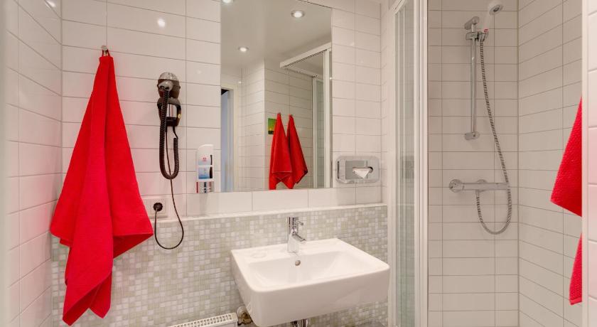 a bathroom with a sink, mirror, and bath tub, MEININGER Hotel Berlin Alexanderplatz in Berlin