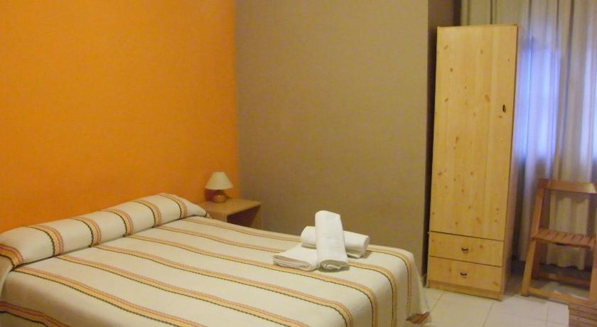 a white bed sitting in a bedroom next to a wall, Pension Corona in Zaragoza