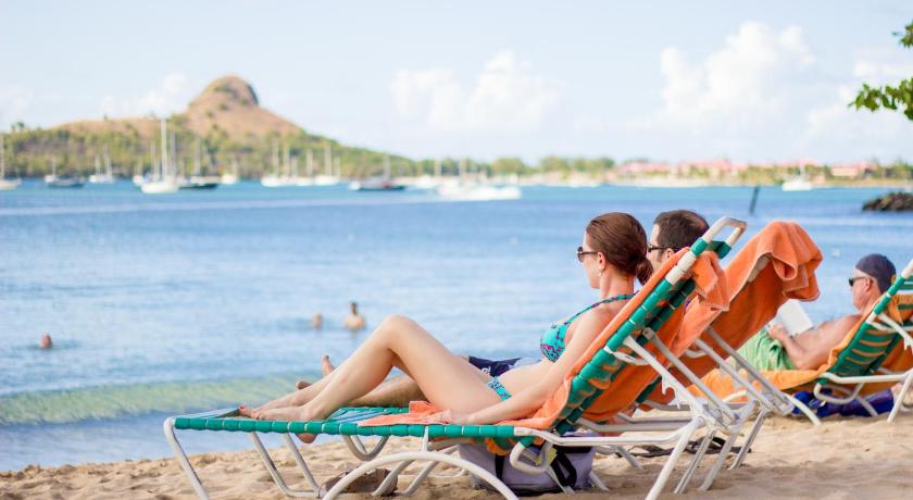 a woman sitting on a bench in the sand, Bay Gardens Beach Resort & Spa in Rodney Bay