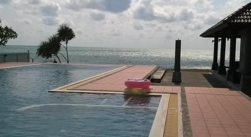 a person standing on the edge of a pool next to a body of water, Khanom Beach Residence in Nakhon Si Thammarat