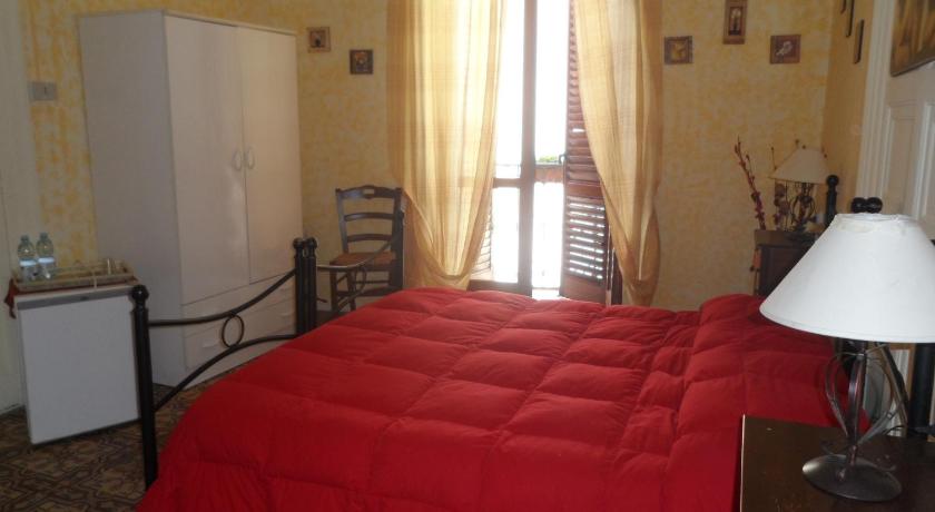 a red bed sitting in a room next to a window, B&B Il Vecchio Messina in Trapani