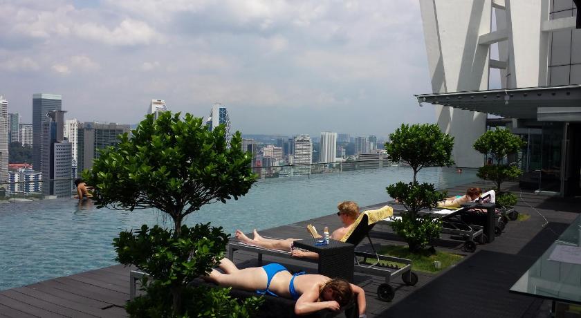 a woman sitting on a bench next to a body of water, The Best KLCC View @ Regalia Residences in Kuala Lumpur