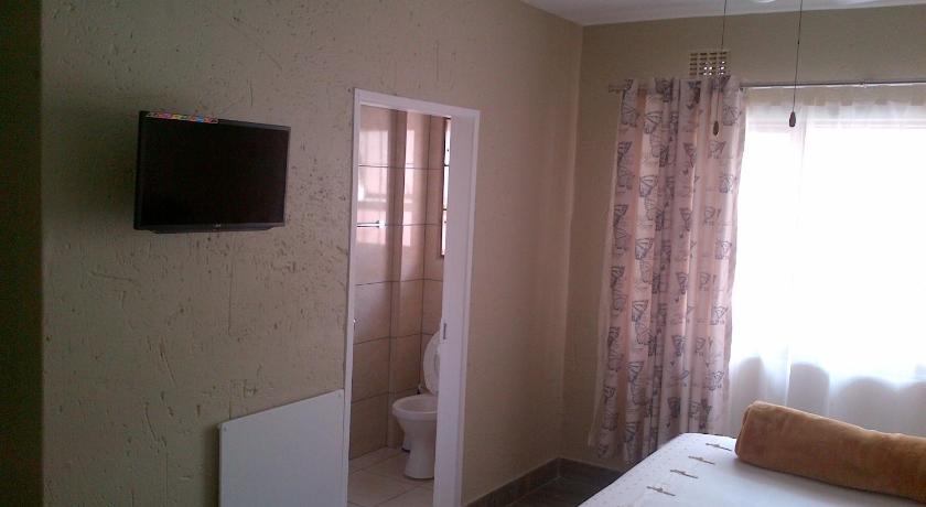 a room with a television and a bed, Chisam Guest Lodge Pty Ltd in Johannesburg