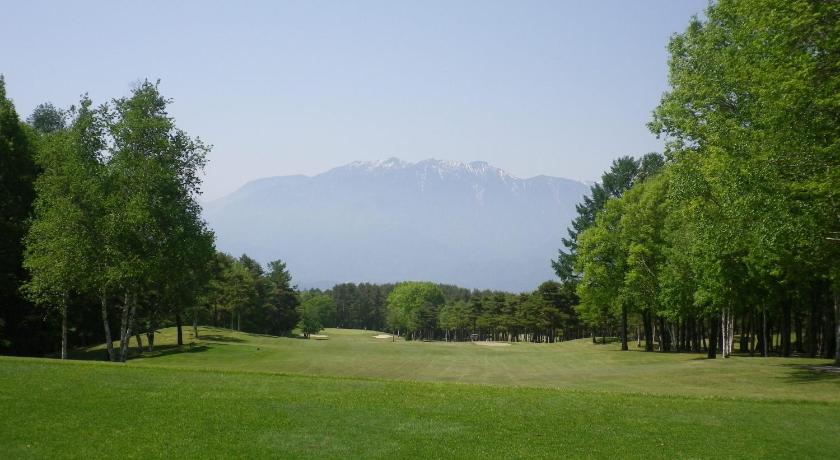a grassy field with trees and a mountain, Hotel Keyforest Hokuto in Hokuto