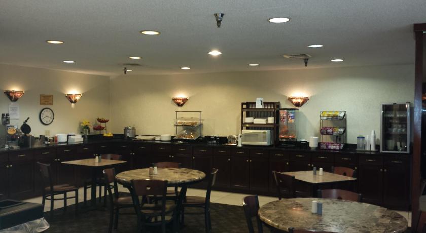a kitchen with a table, chairs, and a refrigerator, Ramada by Wyndham Bettendorf in Bettendorf (IA)