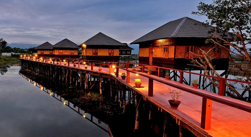 a row of wooden decked boats docked at a pier, Shwe Inn Tha Floating Resort in Inle Lake