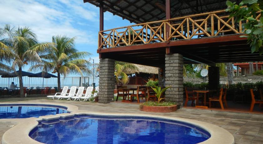 a large swimming pool with a large wooden table in front of it, Punta Roca Surf Resort in La Libertad
