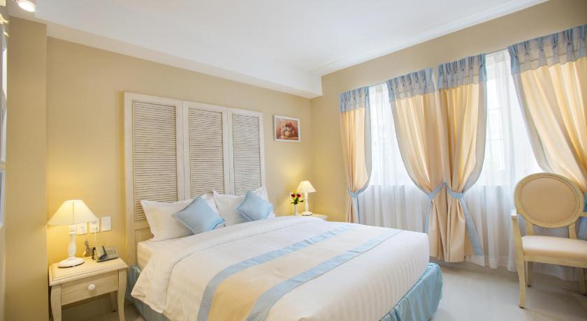 a bedroom with a large bed and a large window, Hotel L Odeon Phu My Hung in Ho Chi Minh City