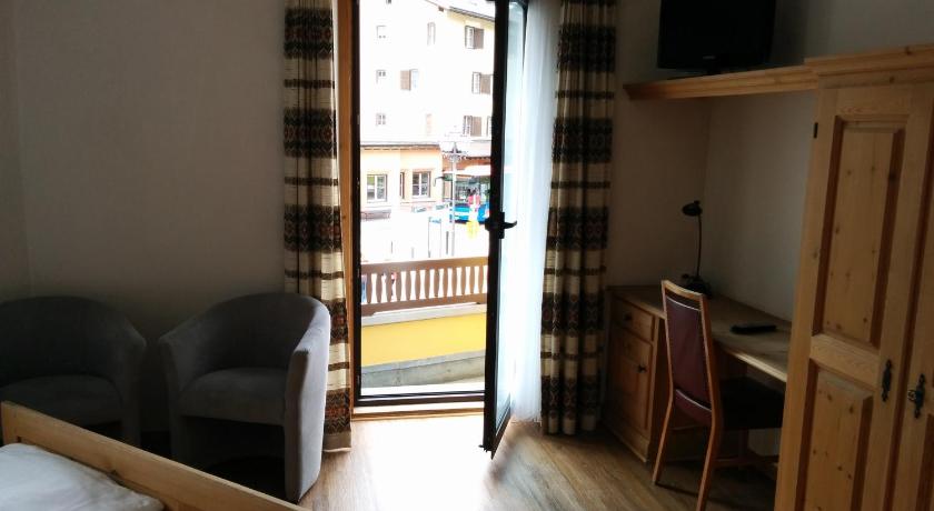 a living room with a bed and a tv, Hotel Terminus in Samedan