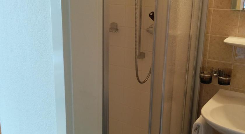 a bathroom with a shower, toilet and sink, Hotel Terminus in Samedan