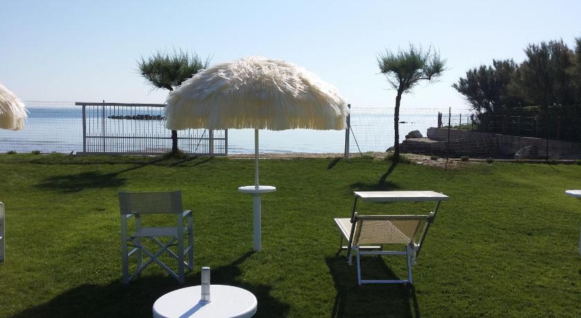a white umbrella sitting on top of a grass covered lawn, Agriturismo Frontemare in Roseto degli Abruzzi