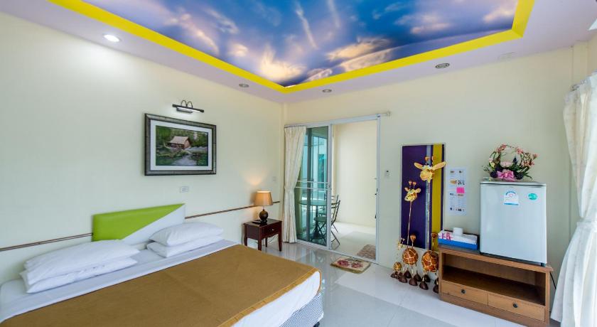 a bedroom with a bed, a desk, and a painting on the wall, Poomvarin Resort in Nakhon Nayok