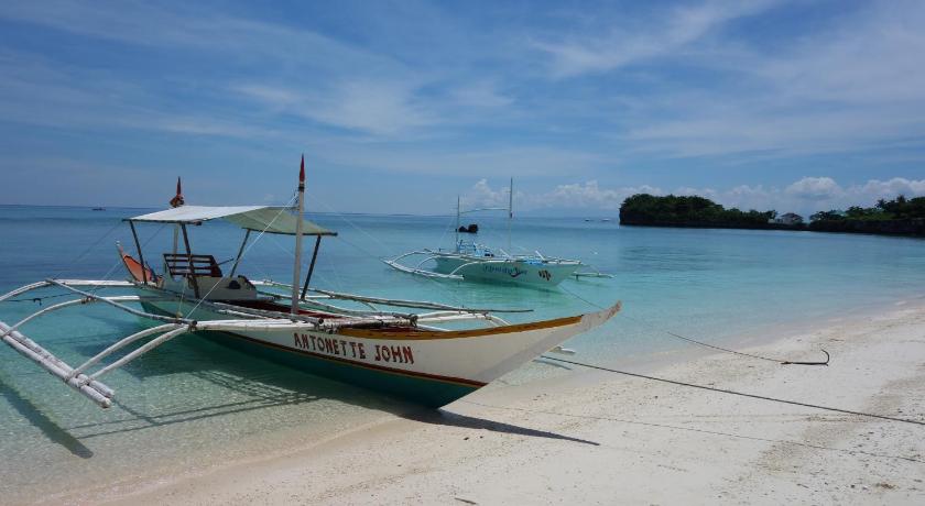 a boat sitting on top of a sandy beach, Slam's Garden Dive Resort in Cebu