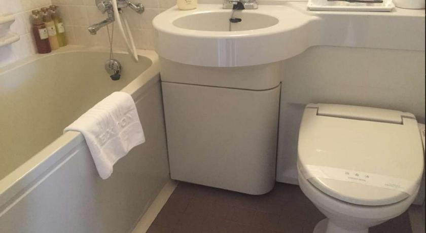 a white toilet sitting next to a sink in a bathroom, Hotel Lexton Kagoshima in Kagoshima