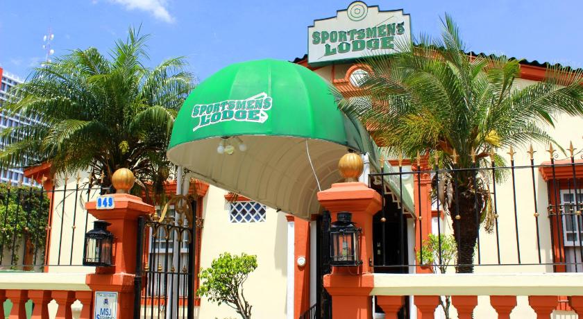 a green and white umbrella sitting under a palm tree, Sportsmens Lodge in San Jose