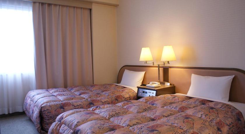 a hotel room with two beds and a lamp, APOA Hotel in Yokkaichi