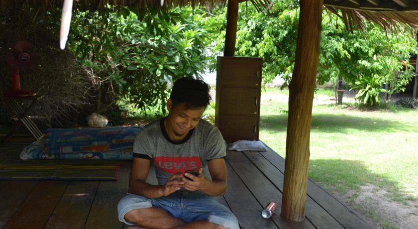 a young man sitting on a bench reading a book, Thai Terrace Bungalow in Ko Pha-ngan