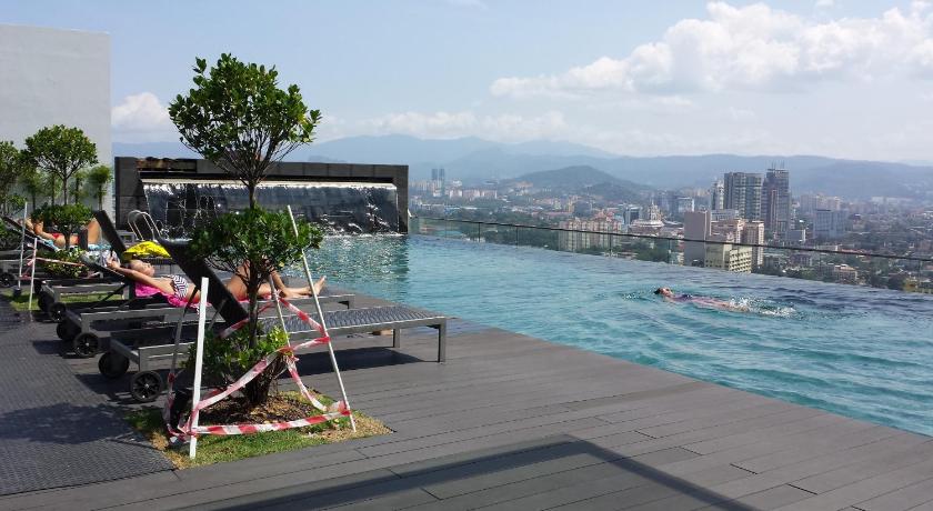 a woman sitting on a bench in front of a body of water, Amazing KLCC View @ Regalia Residence in Kuala Lumpur