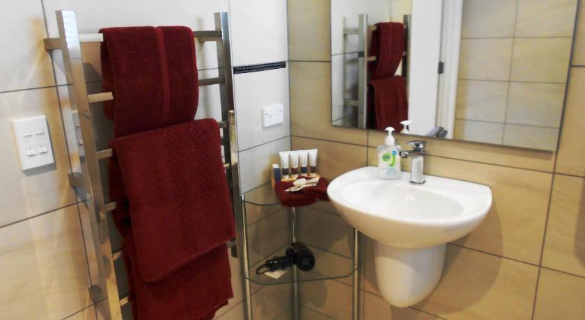 a bathroom with a sink, toilet and mirror, Oneroa Secret Garden Apartments in Waiheke Island