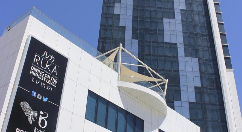 a large white building with a clock on the front of it, Ramee Grand Hotel and Spa in Manama