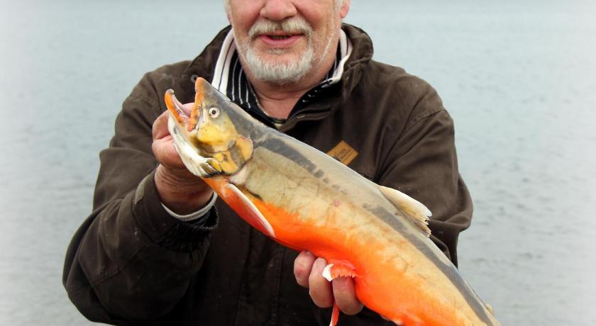 a man holding a fish in front of a body of water, Saivaara Cottages in Kilpisjarvi