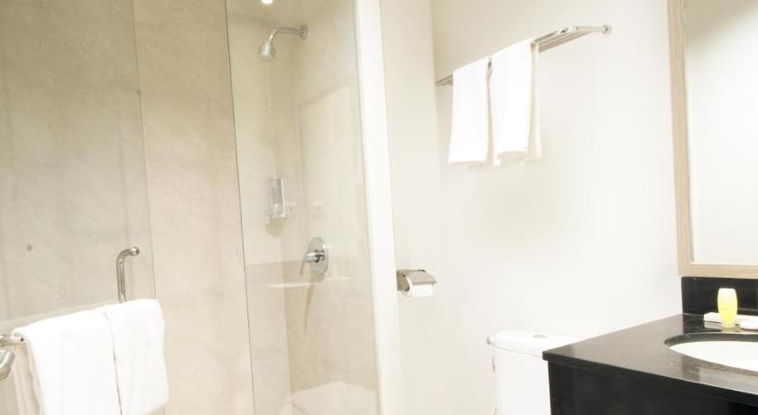 a white toilet sitting next to a shower in a bathroom, Genio Hotel Manado in Manado