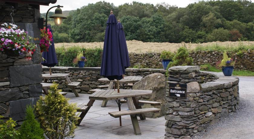 a woman sitting on a bench in front of a stone wall, The Watermill Inn & Brewery in Kendal