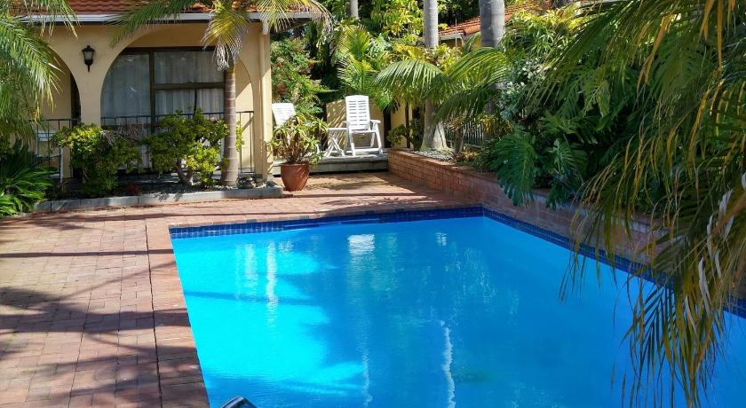 a pool with a lawn chair and a blue chair, Hobson's Choice Motel in Dargaville