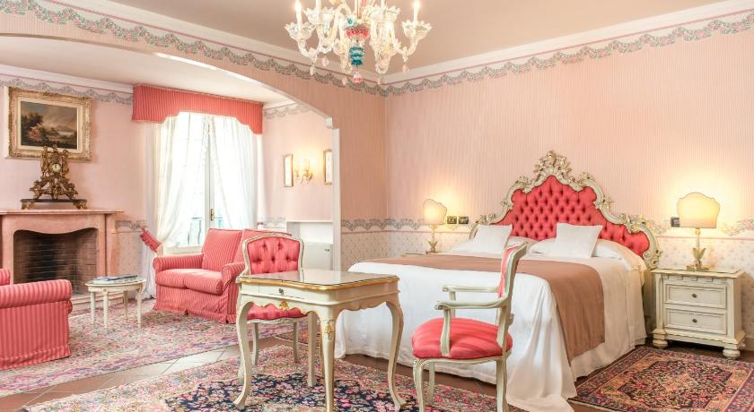 a room with a bed, chair, lamps and a painting on the wall, Duchessa Isabella Hotel & SPA                                                    in Ferrara