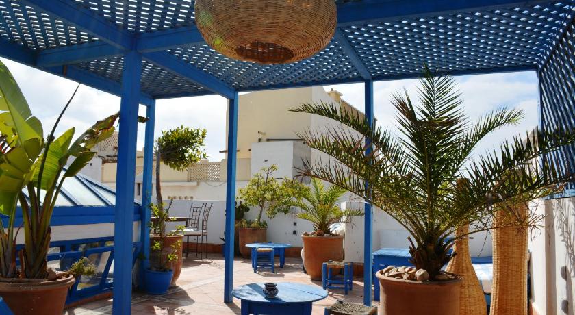 a patio area with a table, chairs, and umbrellas, La Maison Du Vent in Essaouira