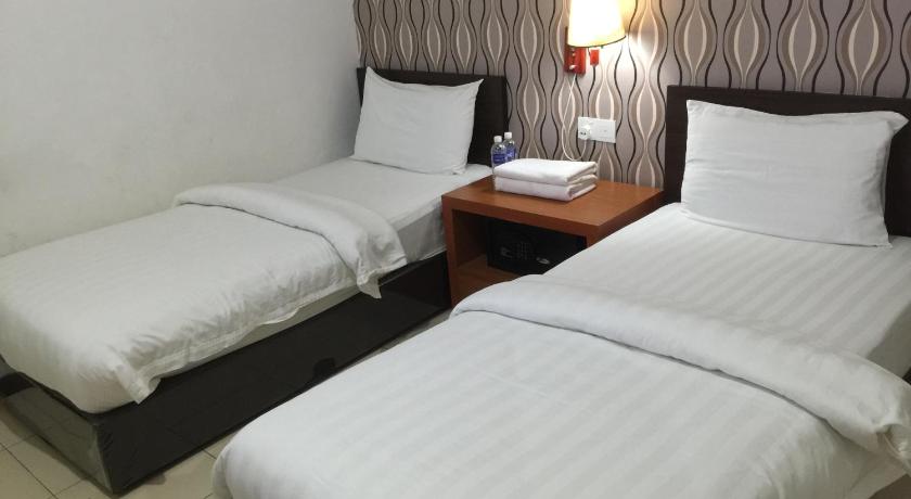 a hotel room with two beds and two nightstands, Permai Hotel in Sibu
