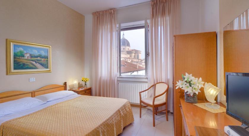 a hotel room with a bed, table, television and a window, San Gabriele in Loreto